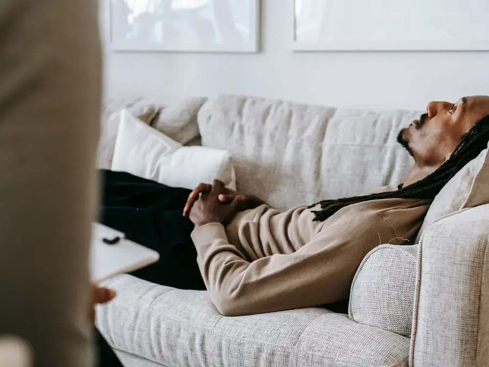 A client resting on a couch while speaking with a counselor during a supportive therapy session