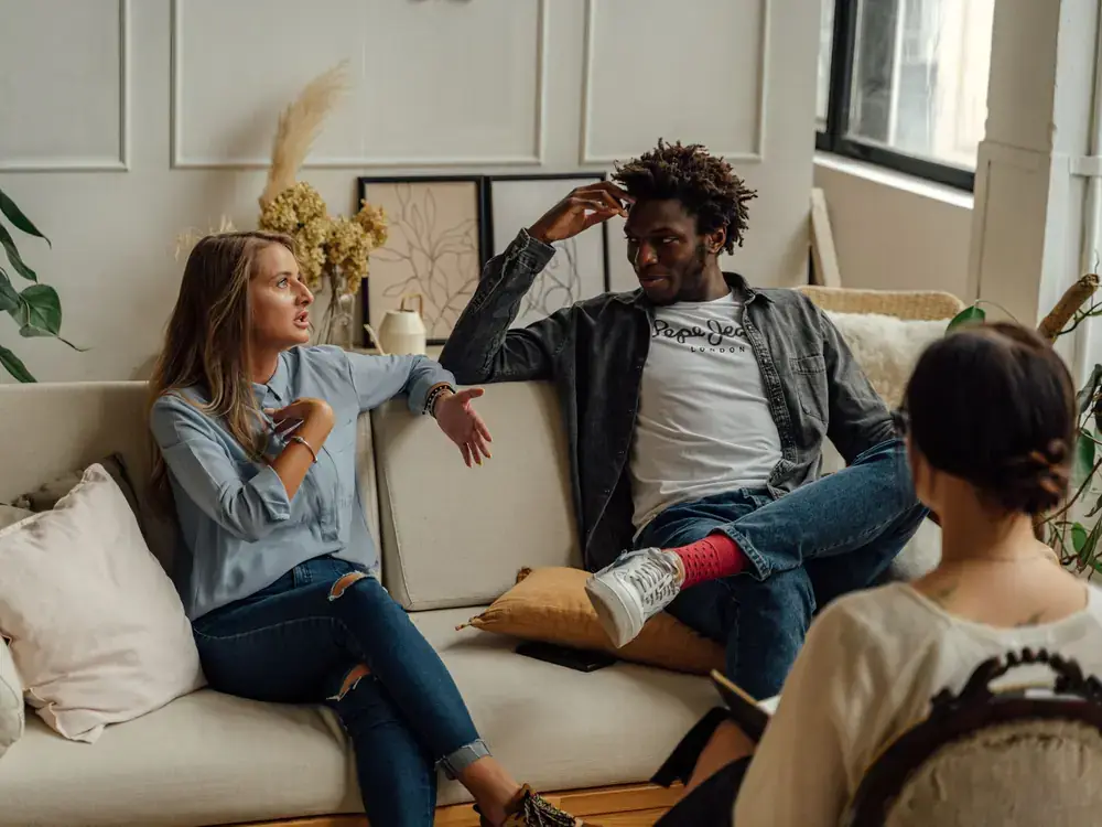 A couple discussing relationship concerns with a therapist in a comfortable office