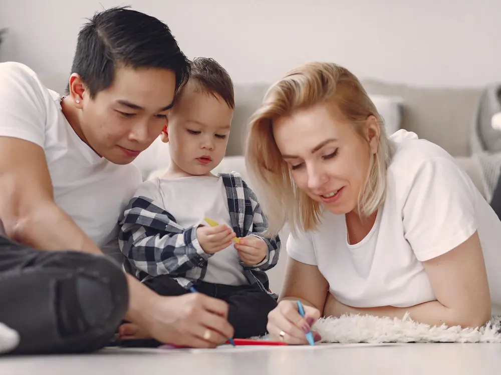 Parents and their young child drawing together during a family activity at home